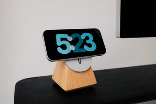 Monolith MagSafe Stand in maple holding an iPhone in landscape orientation on a black oak Desk Shelf — solid hardwood wireless charging stand for desk setup