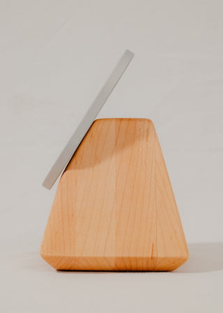 Round white device with black center on a wooden stand against a plain background
