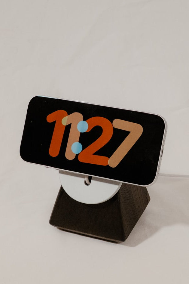 Phone with digital clock display on a stand against a white background