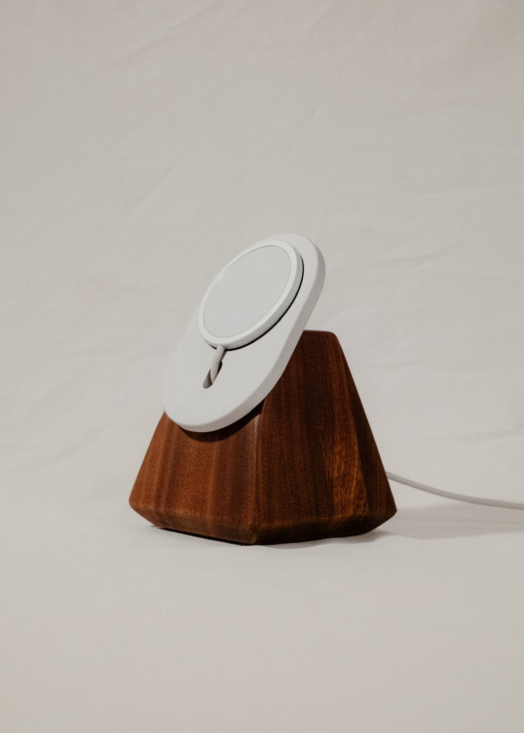 Wooden stand with a white circular object on a plain background