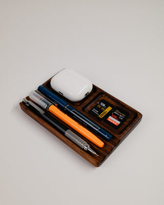 Monolith Desk Tray in walnut styled with AirPods, pens, and small desk items in compartments