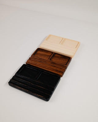 Monolith Desk Tray in maple, walnut and black oak stacked — angled view showing warm wood tones and tray construction