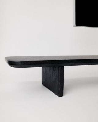 Monolith Desk Shelf corner and leg detail in black oak — softly rounded edges and solid hardwood angled foot
