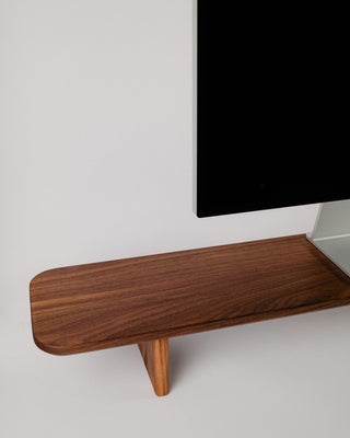Close-up of Monolith Desk Shelf leg detail in walnut — handcrafted angled support with visible wood grain texture