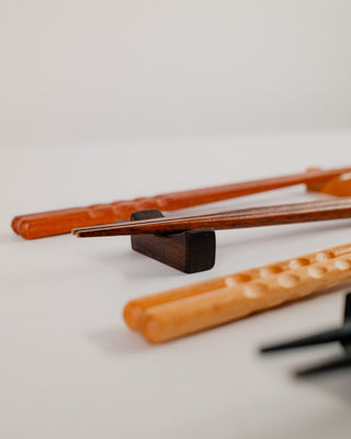 Angled view of chopsticks resting on walnut wood chopstick rests