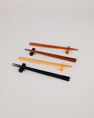 Angled close-up of black and natural chopsticks on solid wood rests