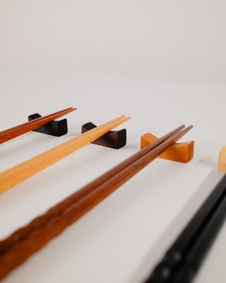 Close-up of chopsticks resting on Indian laurel, walnut and cherry wood rests