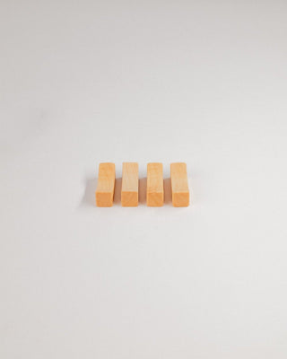 Four maple chopstick rests in a row on a light gray background