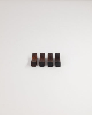 Four walnut chopstick rests lined up on a light gray background